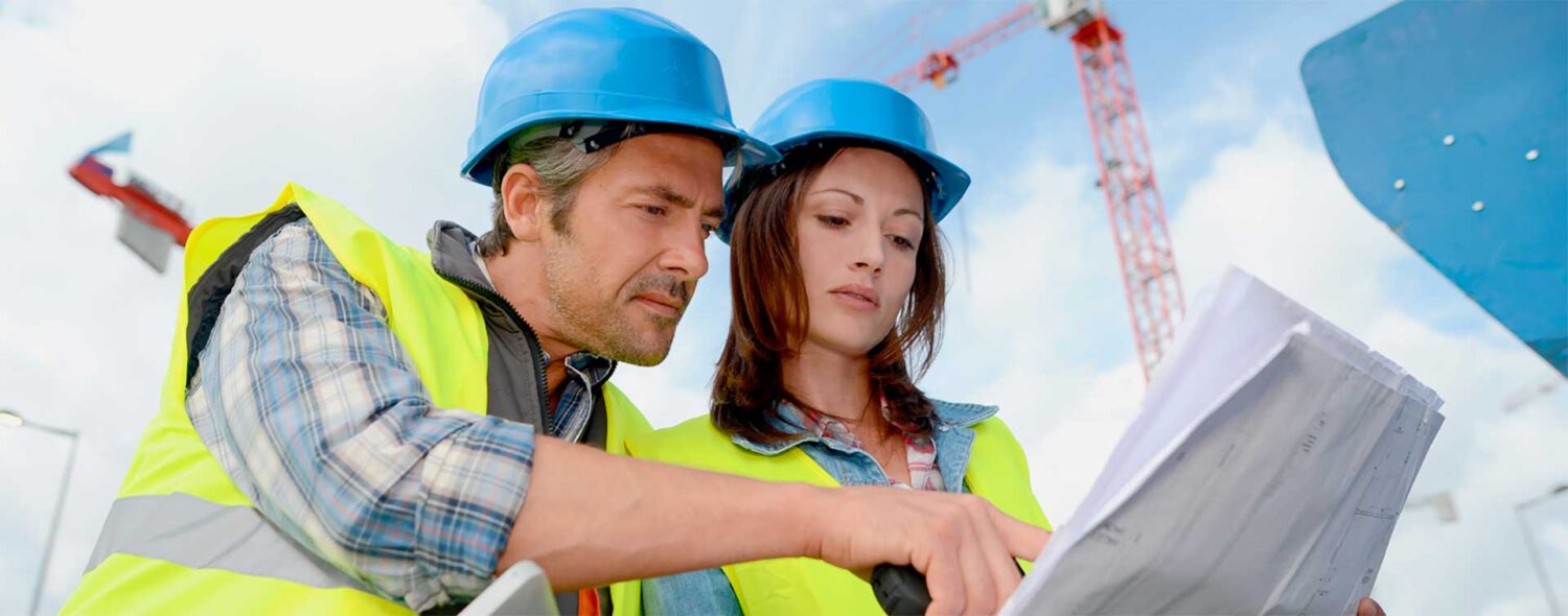 Deux professionnels du BTP consultant les plans d'un chantier